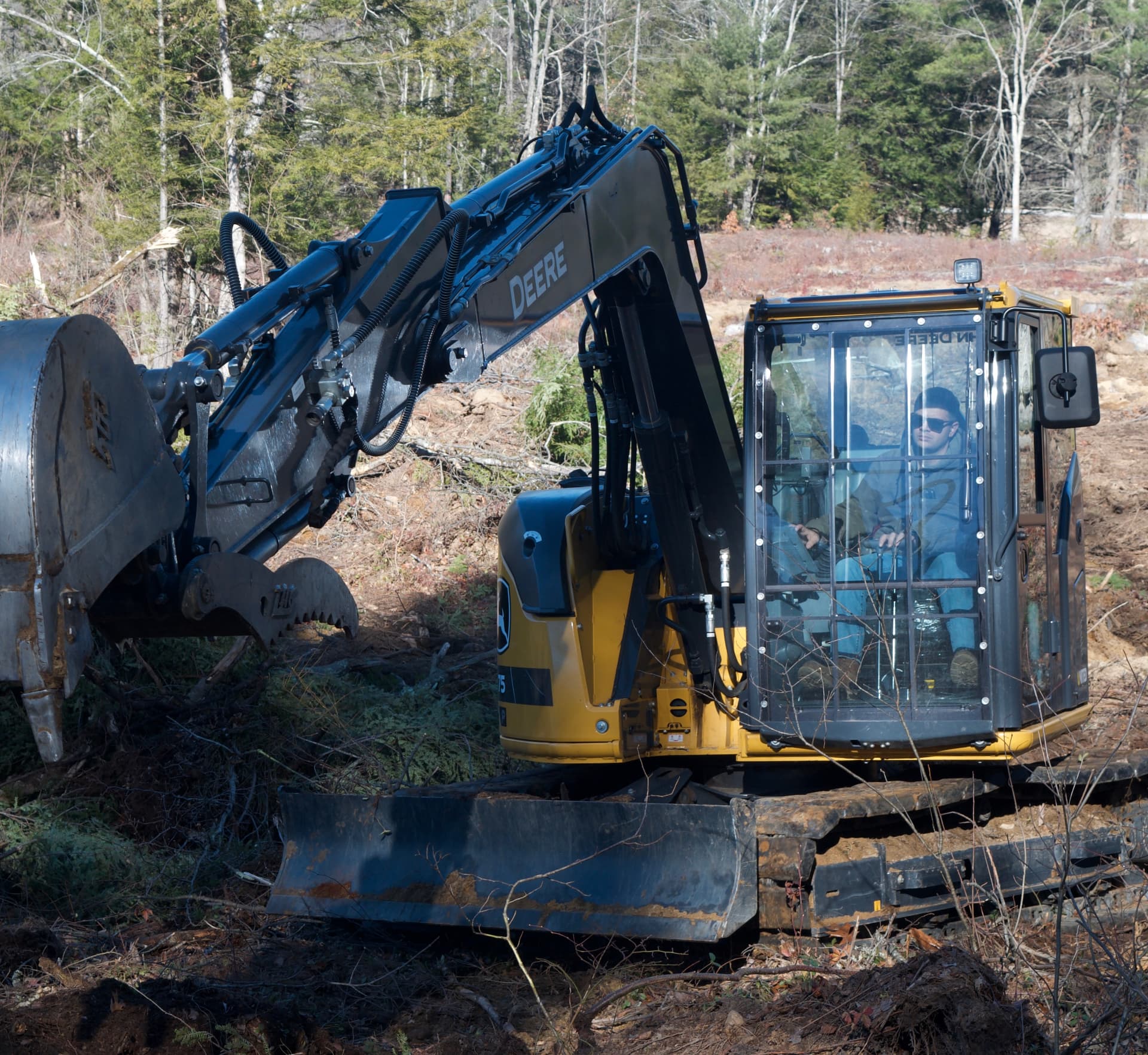 Evan Crafts in the cab of the excavator, clearing a treeline on a New Hampshire property